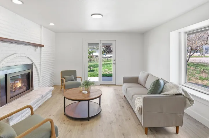 Bright interior space featuring wood-finish flooring, a white brick fireplace with a wood mantle, and sliding glass doors
