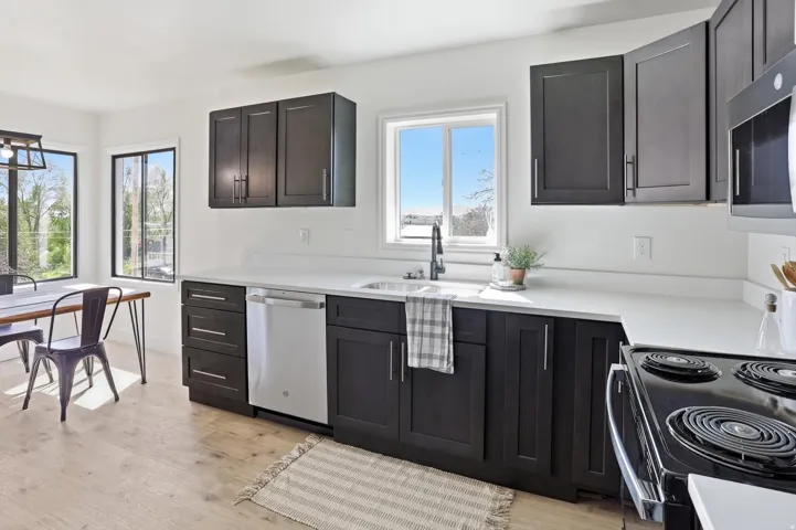 Kitchen featuring dark wood-finish cabinetry with silver hardware, light-toned countertops, and light wood-finish flooring