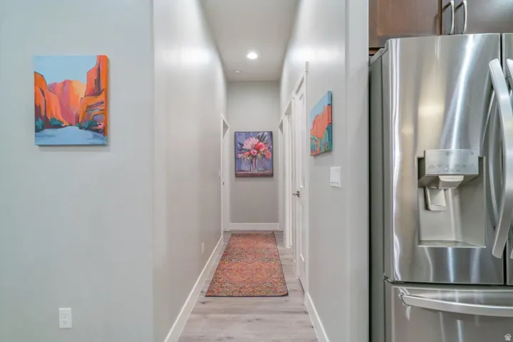 Hallway with light wood-type flooring and recessed lighting