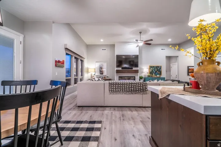 Living room featuring a ceiling fan, light wood-type flooring, a fireplace, and recessed lighting