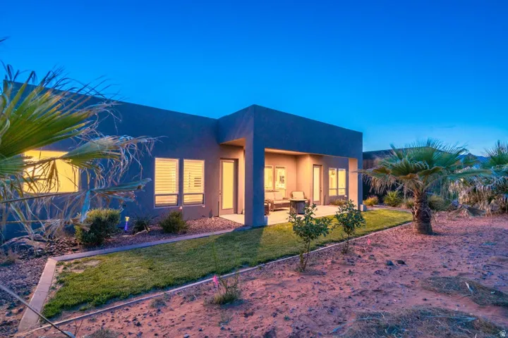 Back of house at dusk featuring stucco siding, a patio area, and a yard