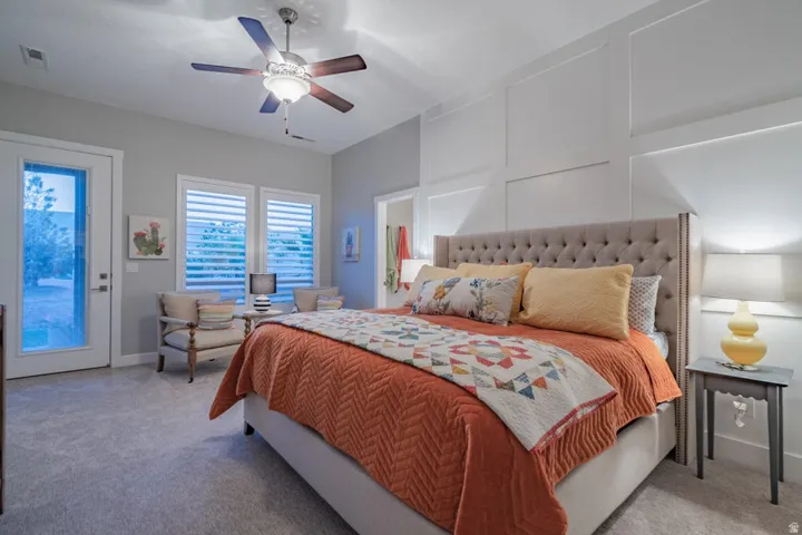 Bedroom featuring a decorative wall, access to outside, light carpet, and a ceiling fan