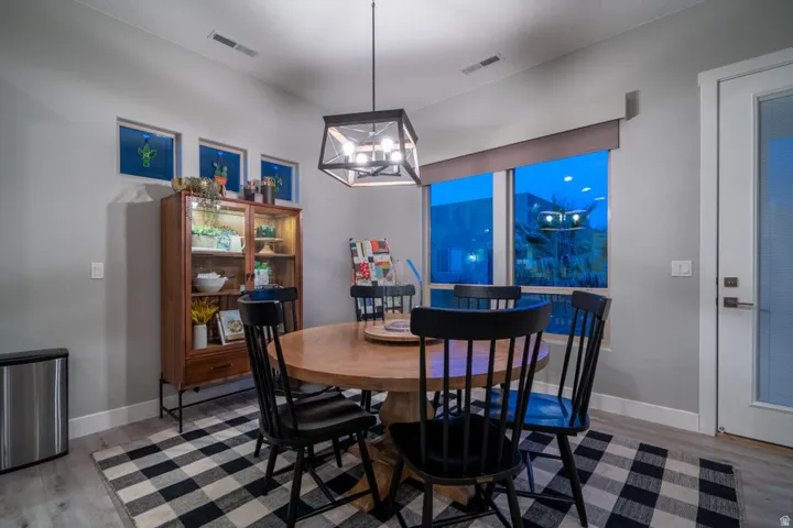 Dining room with light wood-type flooring and suspended lighting
