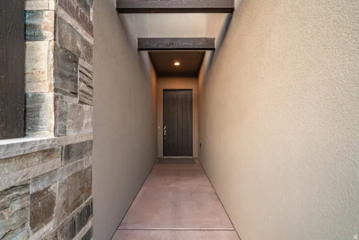 Doorway to property featuring stucco siding and stone siding