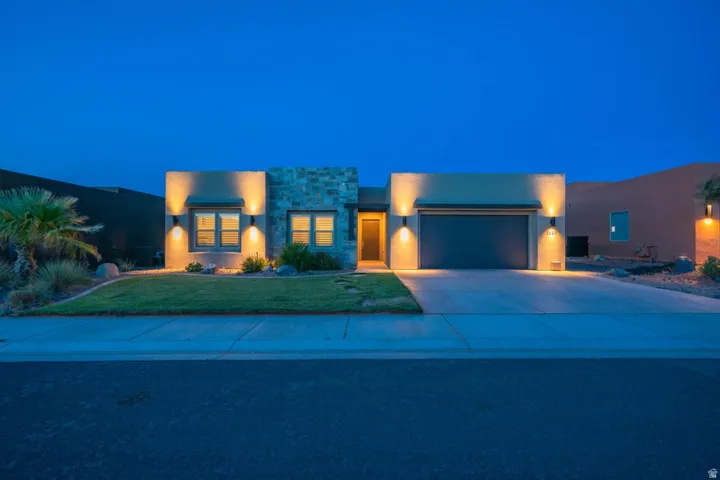 Contemporary home with stone siding, stucco siding, a garage, driveway, and a lawn