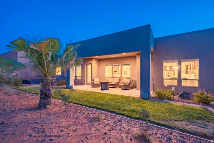 Back of house with stucco siding, a lawn, a patio, and outdoor seating