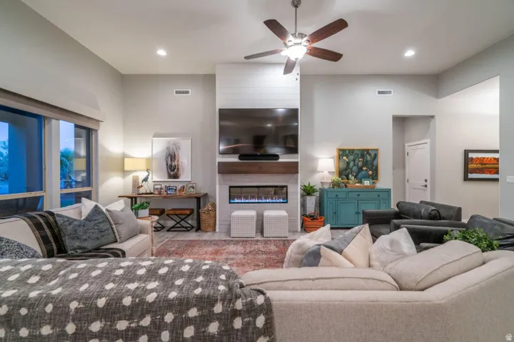 Living area featuring a ceiling fan, a large fireplace, a high ceiling, recessed lighting, and wood finished floors