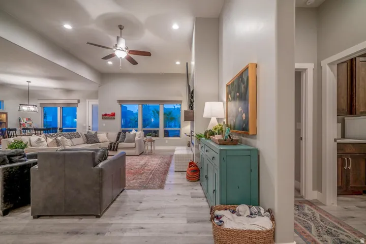 Living room with ceiling fan, light wood-type flooring, a high ceiling, and recessed lighting