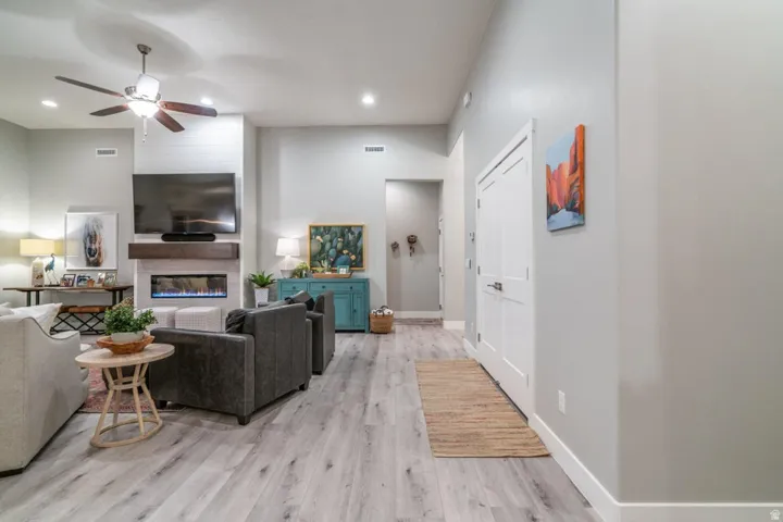 Living room featuring a ceiling fan, a fireplace, light wood finished floors, and recessed lighting