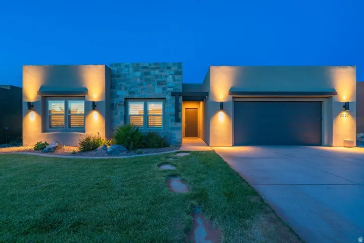Contemporary house with an attached garage, driveway, stucco siding, stone siding, and a yard