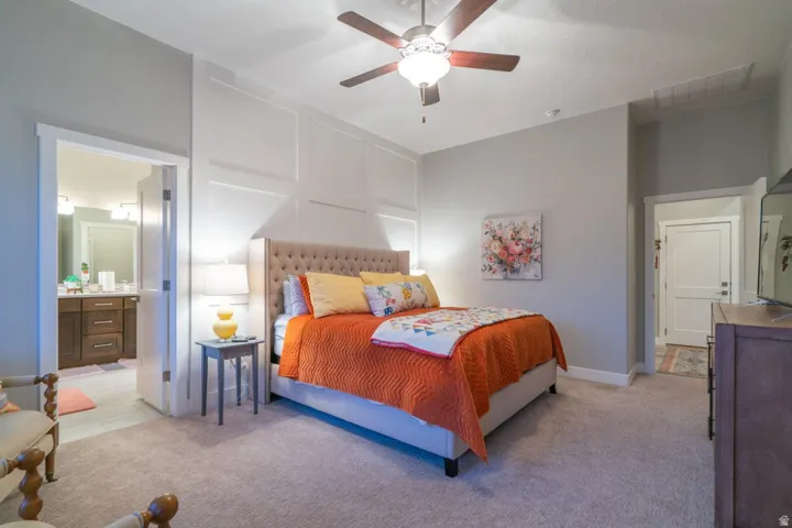 Bedroom featuring ensuite bathroom, light colored carpet, and ceiling fan
