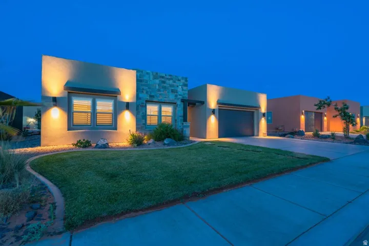 View of front of house featuring a yard, stone siding, and stucco siding