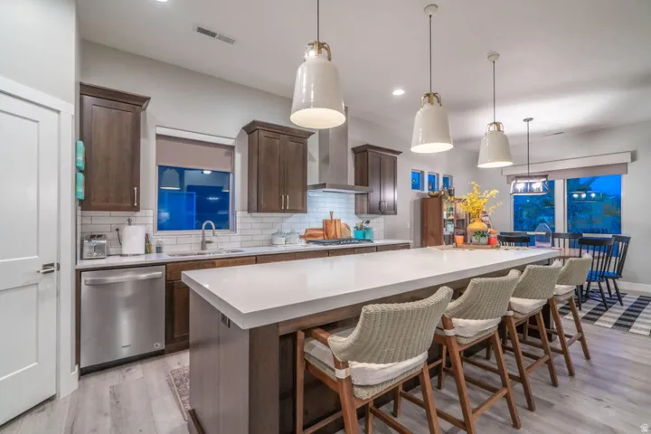 Kitchen with dark wood finish cabinetry, a kitchen breakfast bar, a spacious island, stainless steel appliances, and light wood-style floors