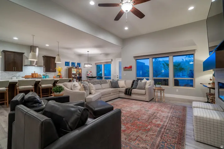 Living room featuring a ceiling fan, light wood-type flooring, a glass covered fireplace, and recessed lighting