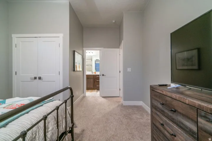 Bedroom with a closet, light carpet, and ensuite bathroom