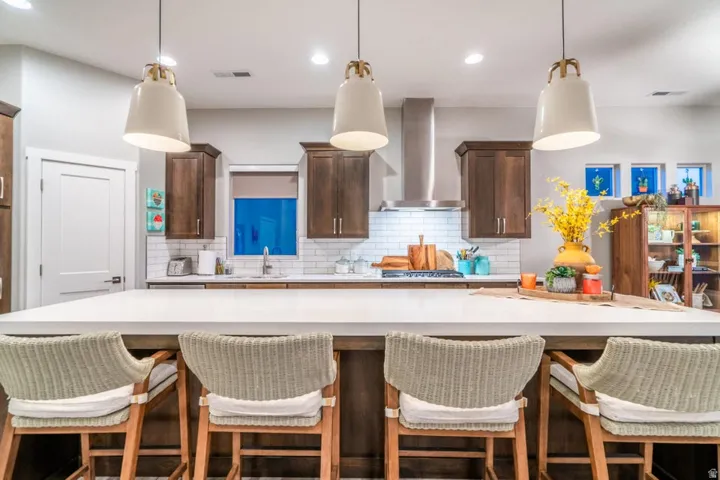Kitchen featuring a breakfast bar, a large island, dark wood finish cabinetry, and hanging light fixtures