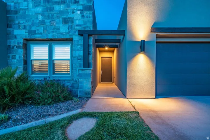Doorway to property with stone siding, stucco siding, and a garage
