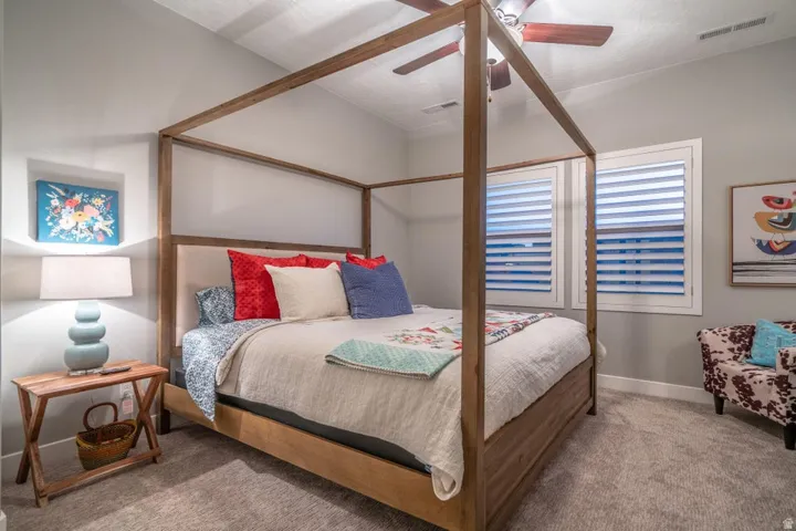 Carpeted bedroom with ceiling fan and baseboards
