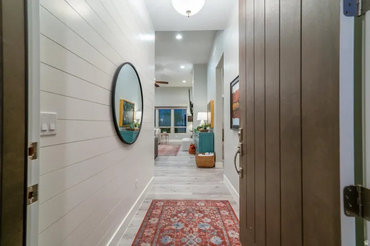 Hallway with light wood-style flooring, recessed lighting, and wooden walls