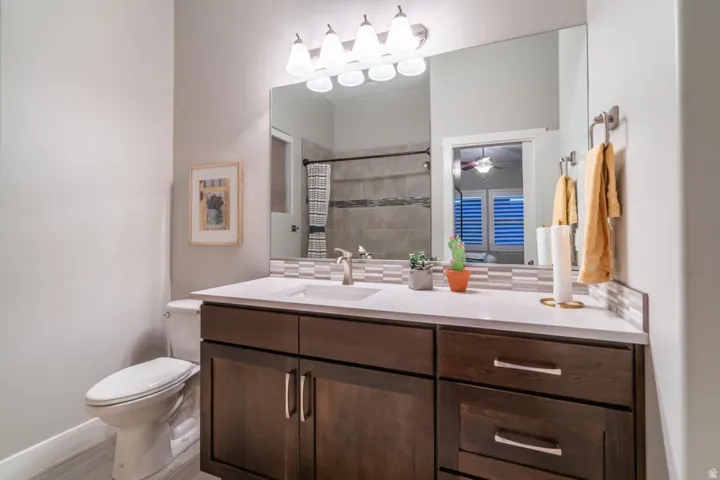 Bathroom with vanity, tiled shower, and ceiling fan