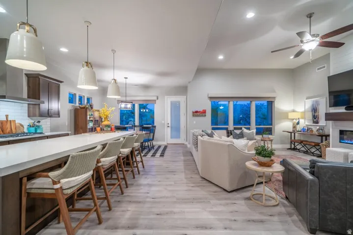 Living area with light wood-style floors, a glass covered fireplace, recessed lighting, and a ceiling fan