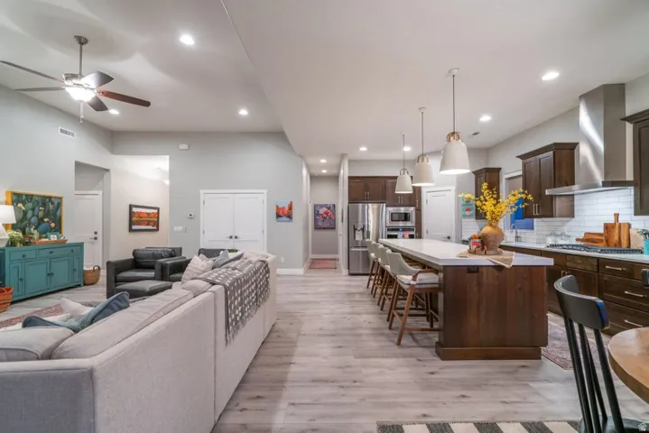 Living room with ceiling fan, light wood-style flooring, recessed lighting, and a high ceiling