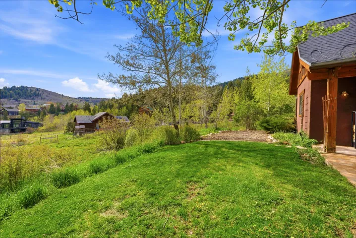 Manicured lawn area with a natural wood-finish porch and a rich brown exterior