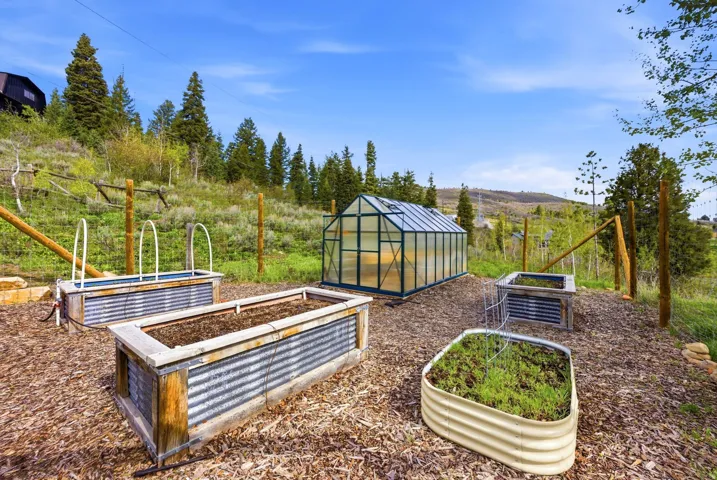 Dedicated garden area featuring a greenhouse structure and multiple raised planter beds