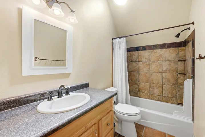 Bathroom featuring a white bathtub, tiled shower surround, and a vanity with an oval sink