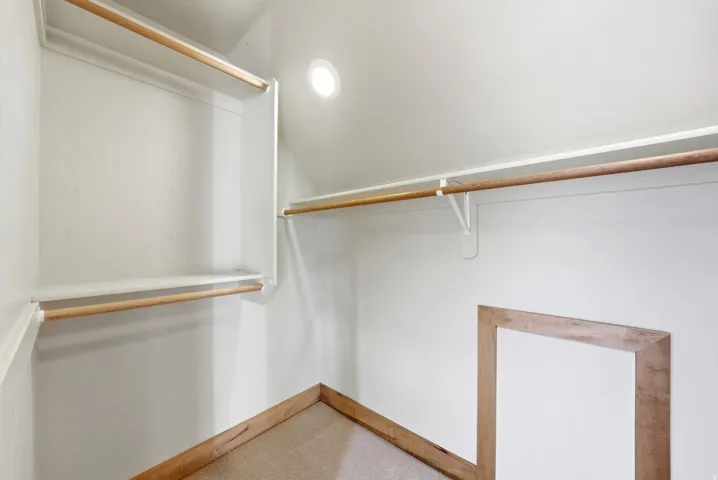 Walk-in closet with integrated shelving, multiple wooden hanging rods, recessed ceiling lighting, and light-toned carpet flooring