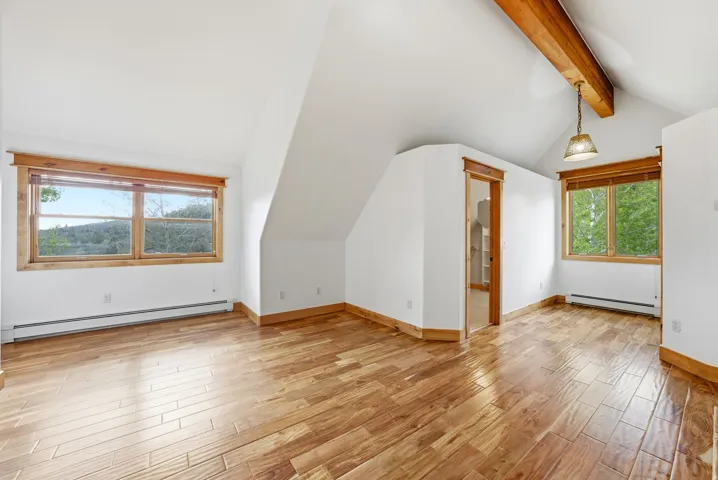 Spacious room with wood-finish flooring and sloped ceilings
