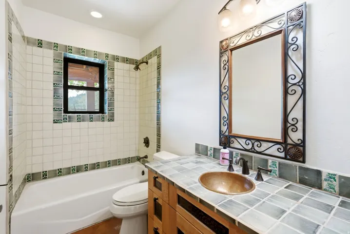 Bathroom featuring a copper vessel sink, tile countertop, and custom wood vanity