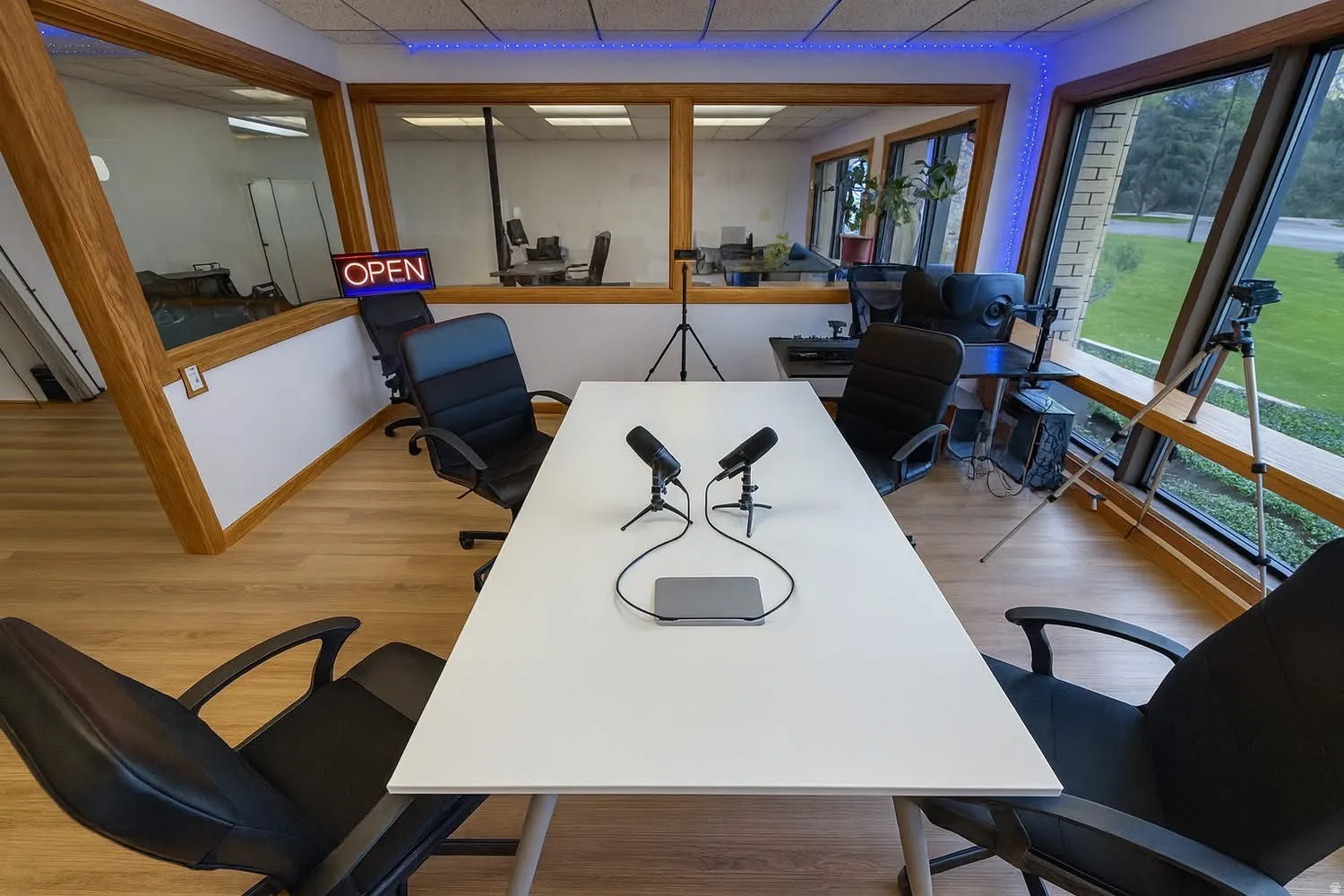 Dedicated workspace featuring wood-finish flooring, angular window design, and a large central table