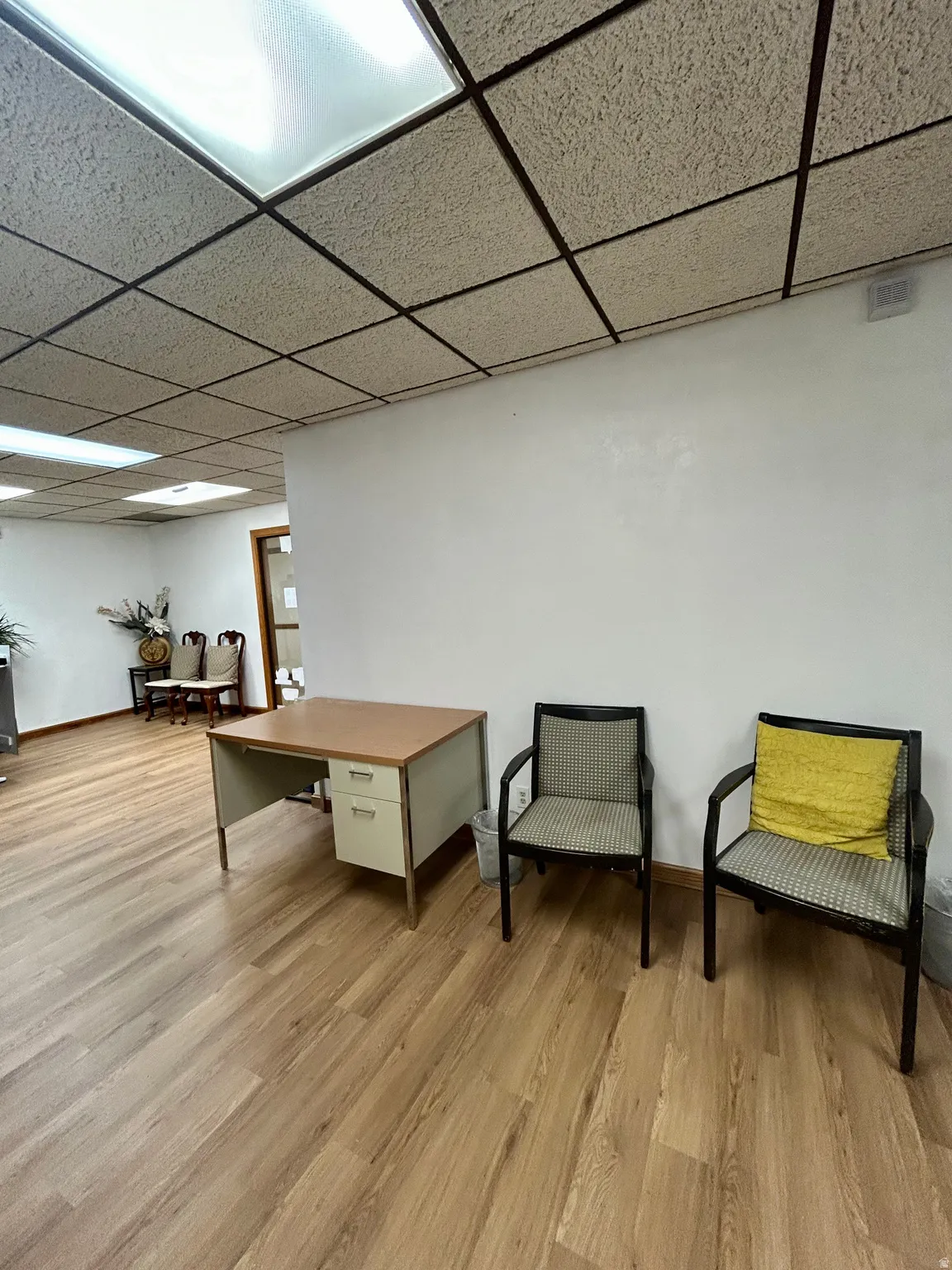 Wood-finish flooring throughout, featuring a drop ceiling with integrated fluorescent lighting