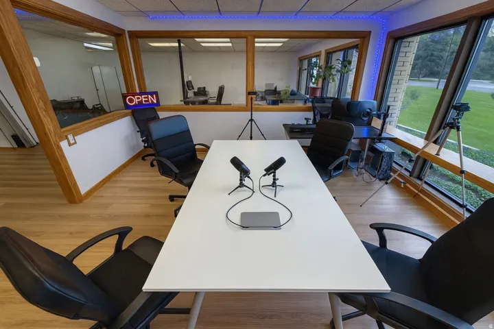 Dedicated workspace featuring wood-finish flooring, angular window design, and a large central table