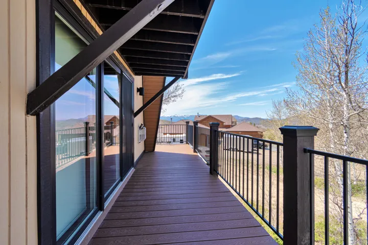 Expansive exterior deck featuring durable composite decking, sleek black metal railings, and a horizontal siding facade