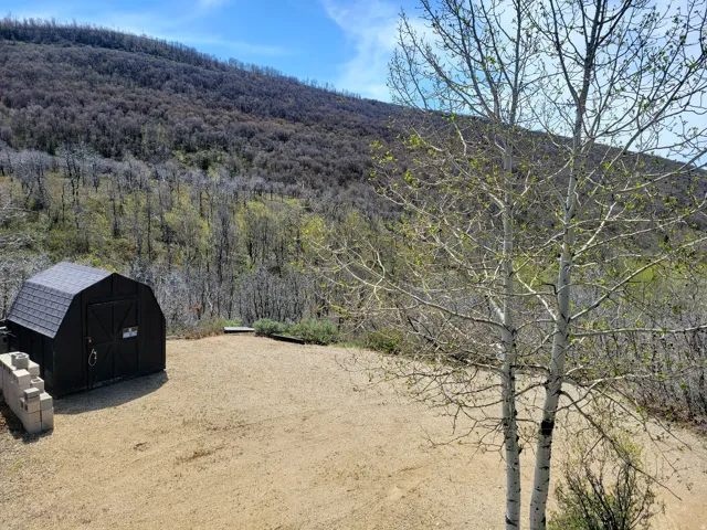 Black gambrel-roof shed on a gravel pad