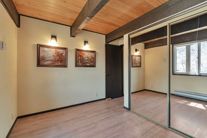 Room featuring wood-finish flooring, exposed wood beams, and a natural wood plank ceiling