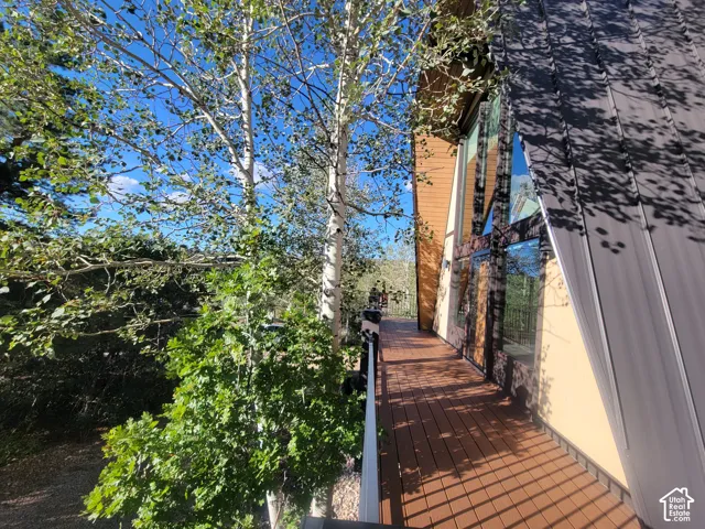 Spacious wood-finish deck with dark railing, large-pane windows, and a metal roof