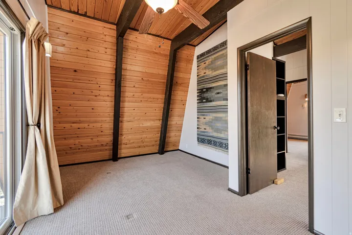 Interior space featuring vaulted ceilings, exposed wood beams, and natural wood plank walls