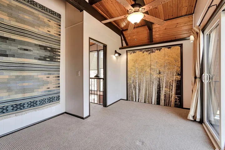 Vaulted wood-paneled ceiling with exposed beams and ceiling fan