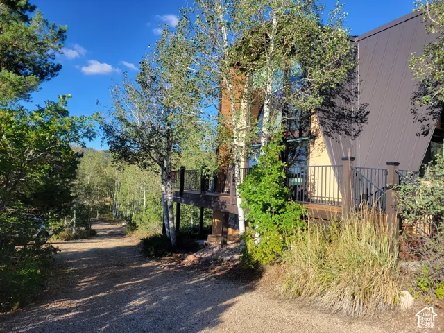 Modern sloped roofline, expansive windows, spacious deck with black railing, and a gravel driveway