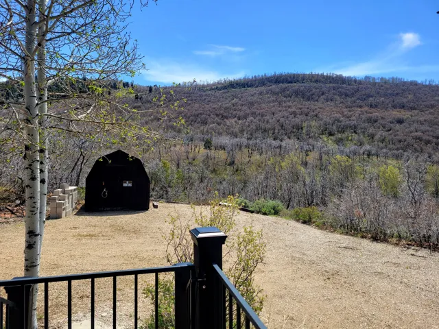Gambrel-style outbuilding with a metal roof, surrounded by a natural landscape