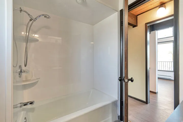 Full white bathtub and shower surround with chrome fixtures, including a handheld showerhead