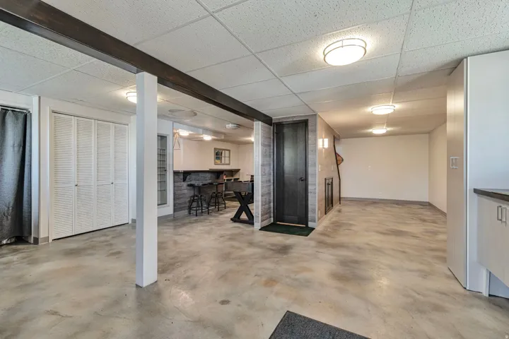 Spacious lower-level area with concrete flooring and a drop ceiling