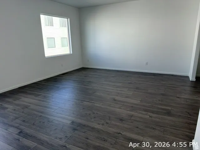 Expansive room featuring wood-finish flooring, white baseboards, and a large window