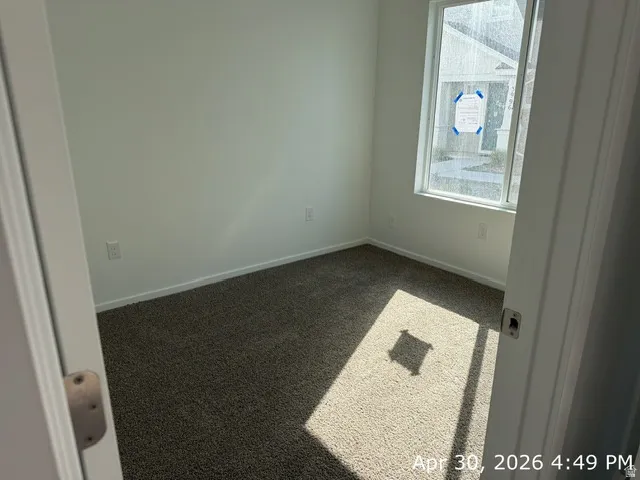 Carpeted interior room with white walls, a single window, and white trim
