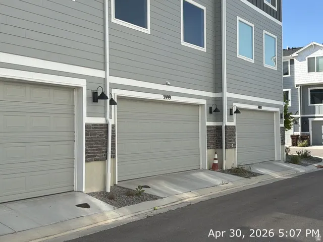 Contemporary townhome exterior featuring light gray horizontal siding, white trim, and individual garage doors