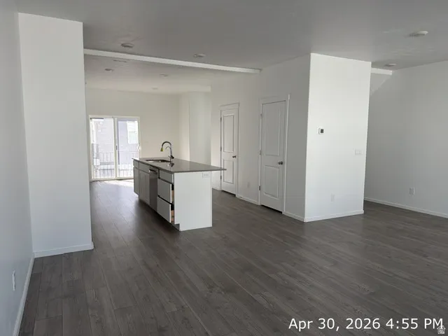 Open-concept living area featuring wood-finish flooring, recessed lighting, and a kitchen island with a sink and modern cabinetry