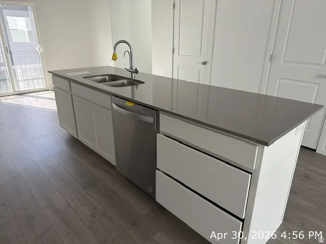 Kitchen island featuring a double basin stainless steel sink, a stainless steel dishwasher, and a gray countertop